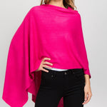 Young woman standing with hand on hip wearing a fuchsia poncho