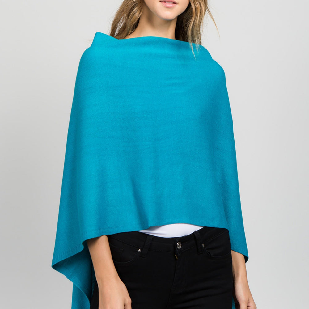 Young woman standing facing front wearing a turquoise poncho