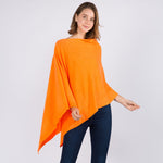 Young woman standing and posing wearing a neon orange colored poncho