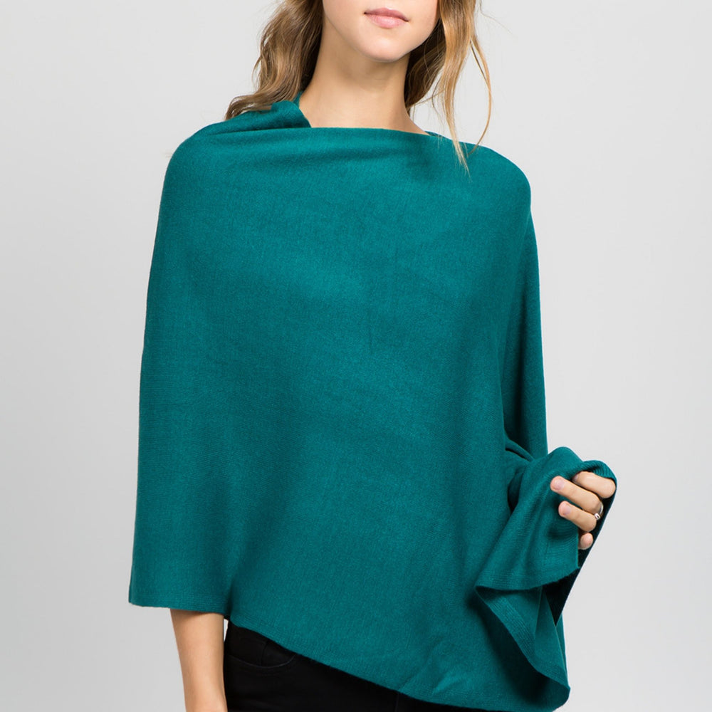 Young standing woman facing front wearing a teal poncho